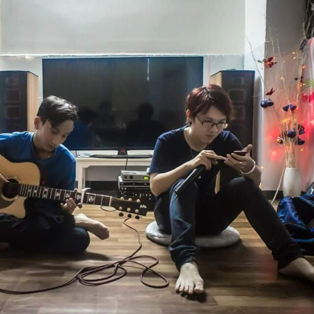 Candid moment of Kenz Tran seated beside a guitarist, balancing his AI leadership at MOCHIMIN with downtime for music and creative recharge.